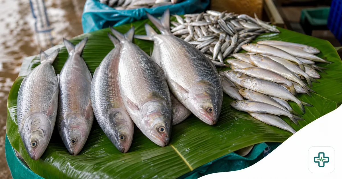 Fresh whole ilish fish and small local fish displayed on banana leaves at a Bangladeshi market, glistening in daylight